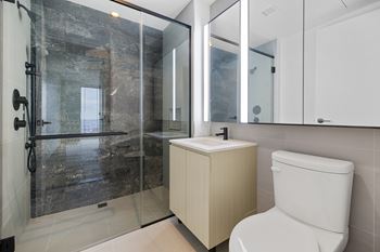 Bathroom - smooth matte light grey porcelain walls and flooring with accent eros grey honed marble wall